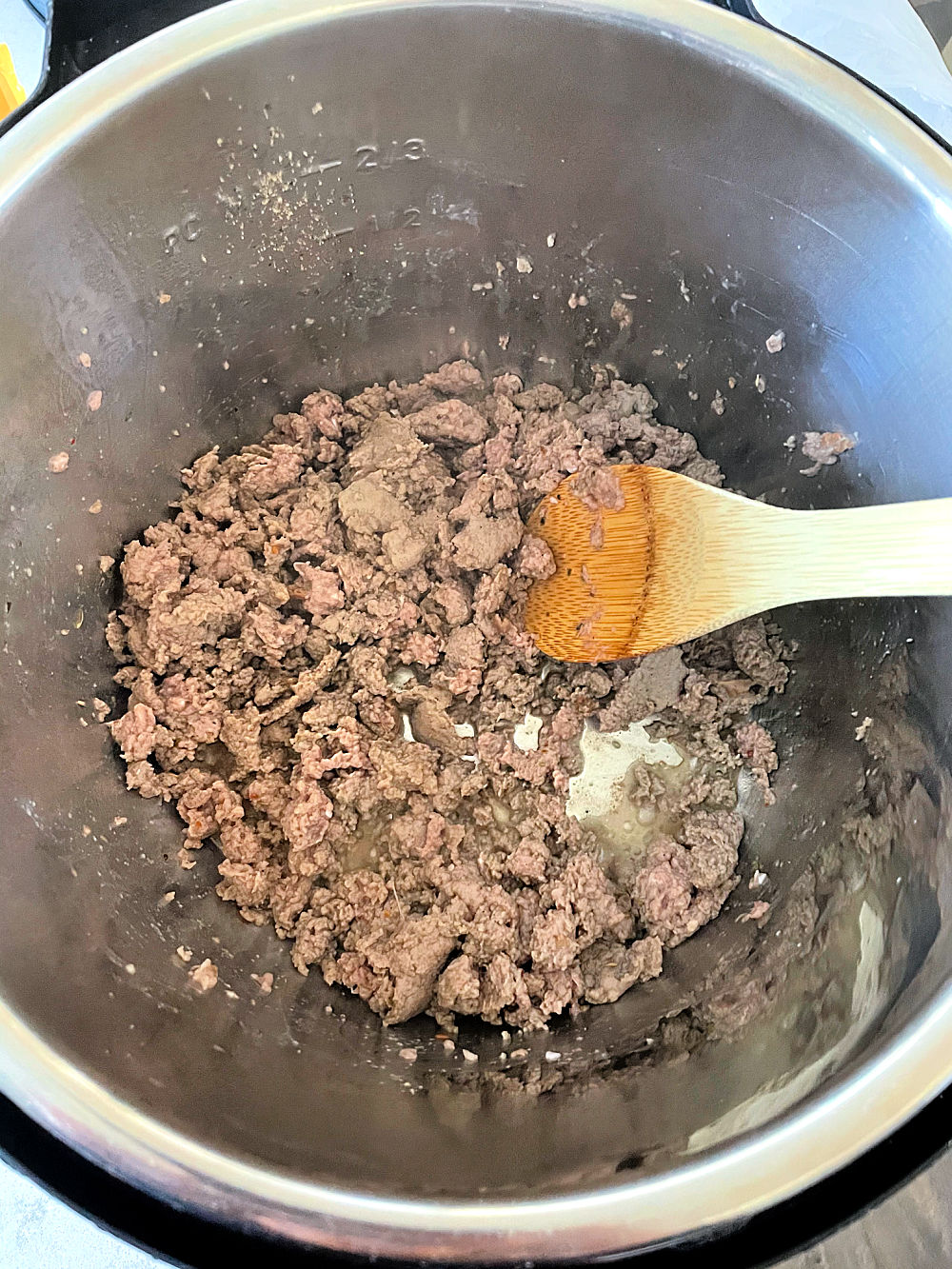 Ground Beef cooked in the Instant Pot with a wooden spoon