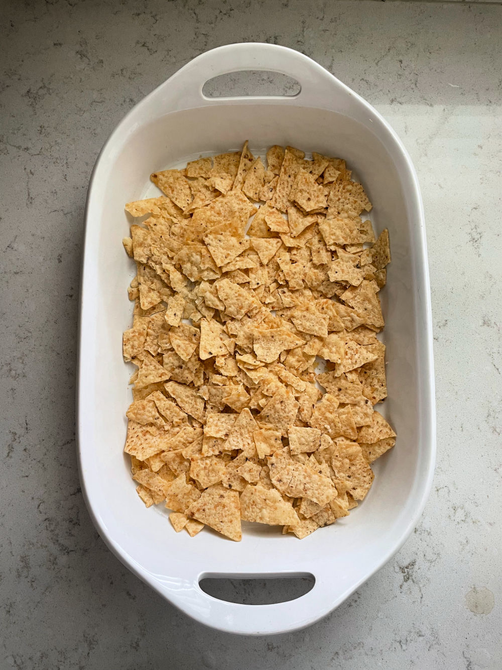 crushed tortilla chips in the bottom of a pan