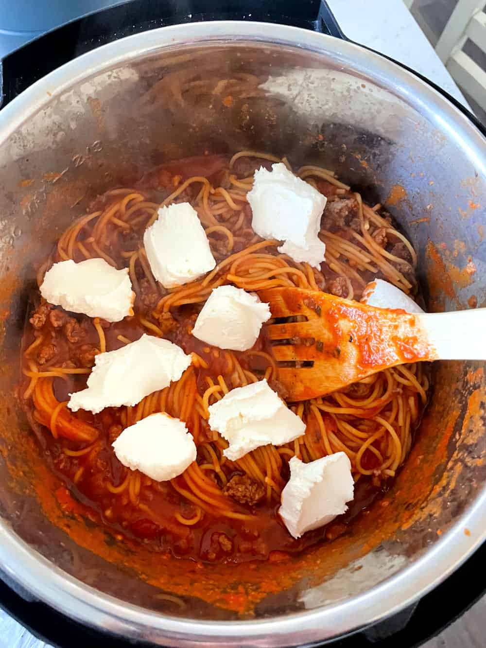 Cream cheese spoonfuls on top of cooked spaghetti