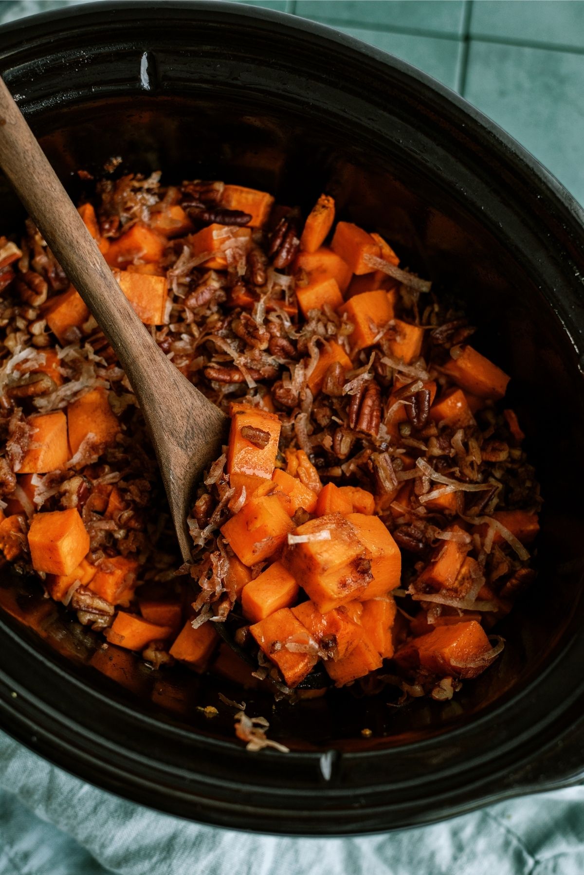 Coconut Pecan Sweet Potatoes in the Slow Cooker with a wooden spoon