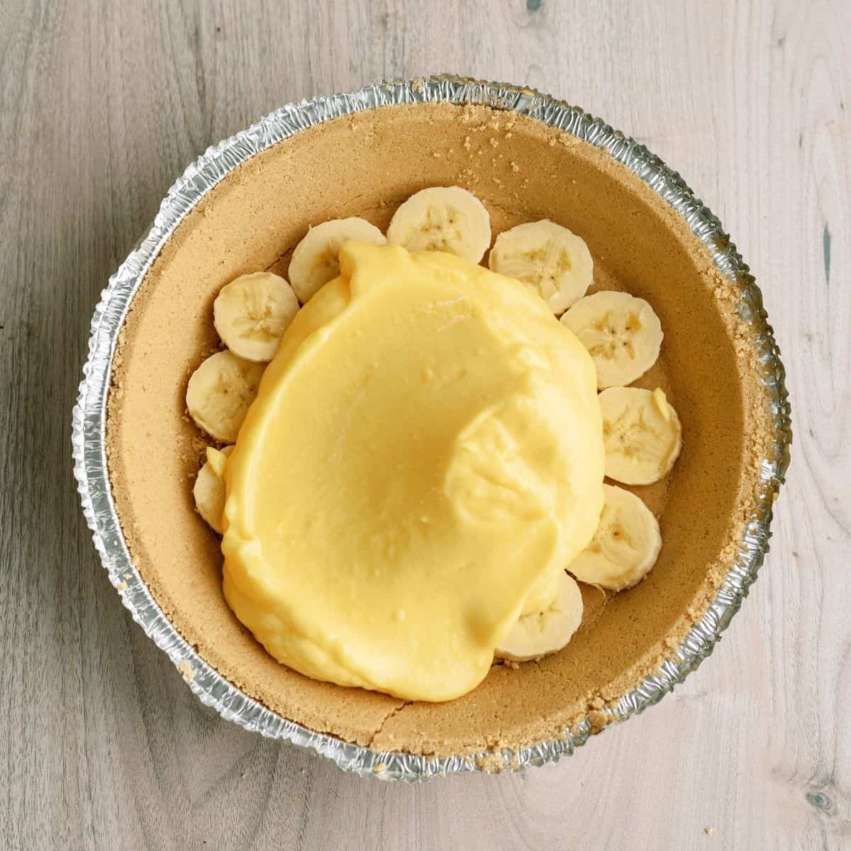 Spreading half the pudding mixture on top of the sliced bananas