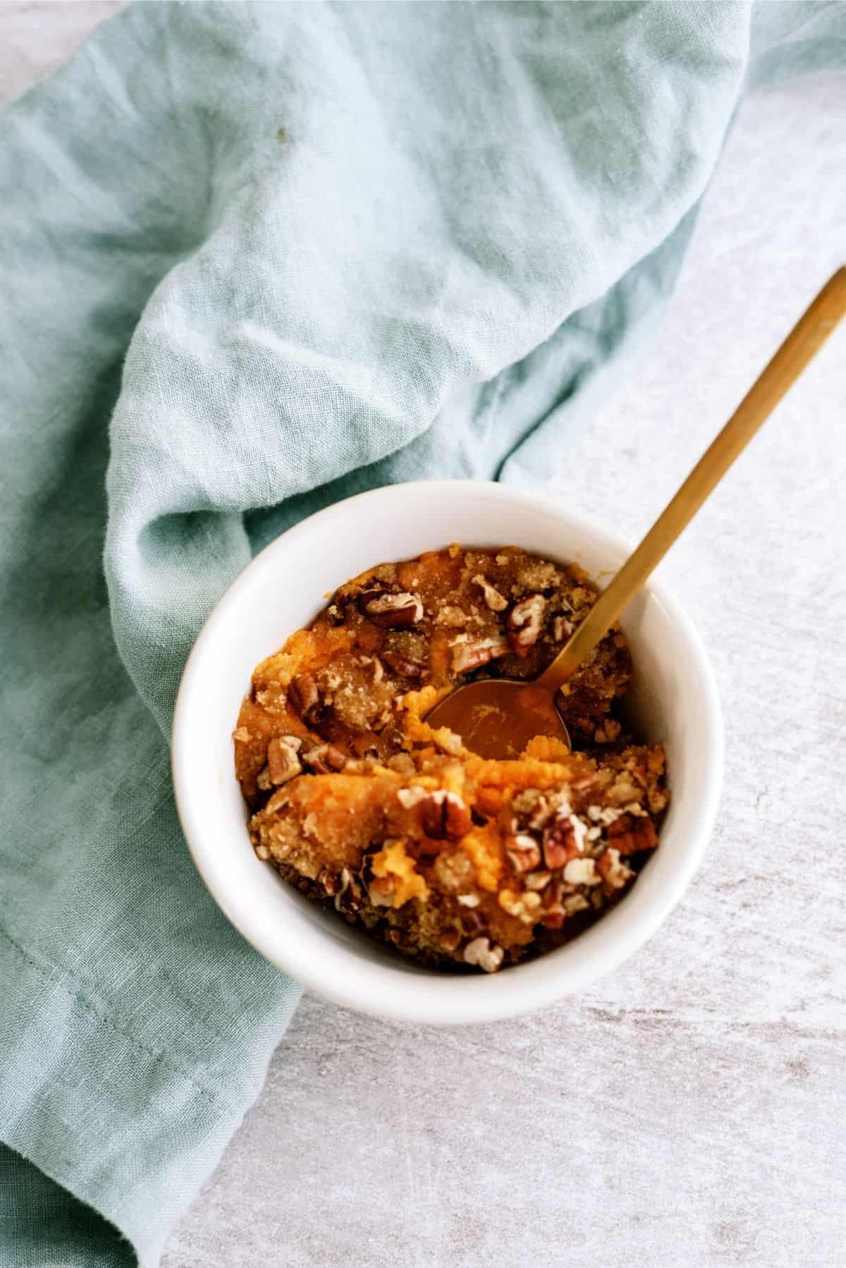 Serving of Mom’s Sweet Potato Casserole served in a white bowl with a spoon