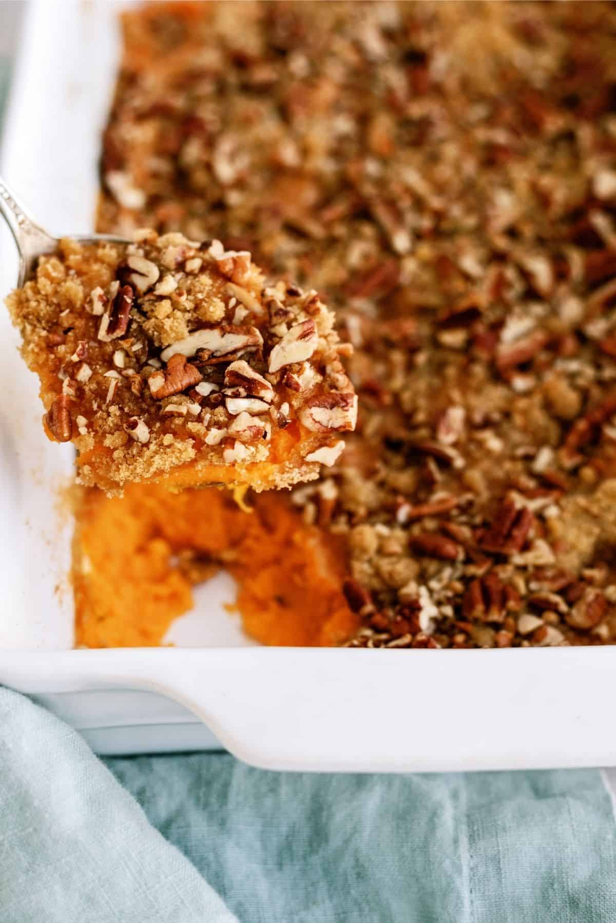 Baked Mom’s Sweet Potato Casserole in casserole dish with a spoon full of casserole