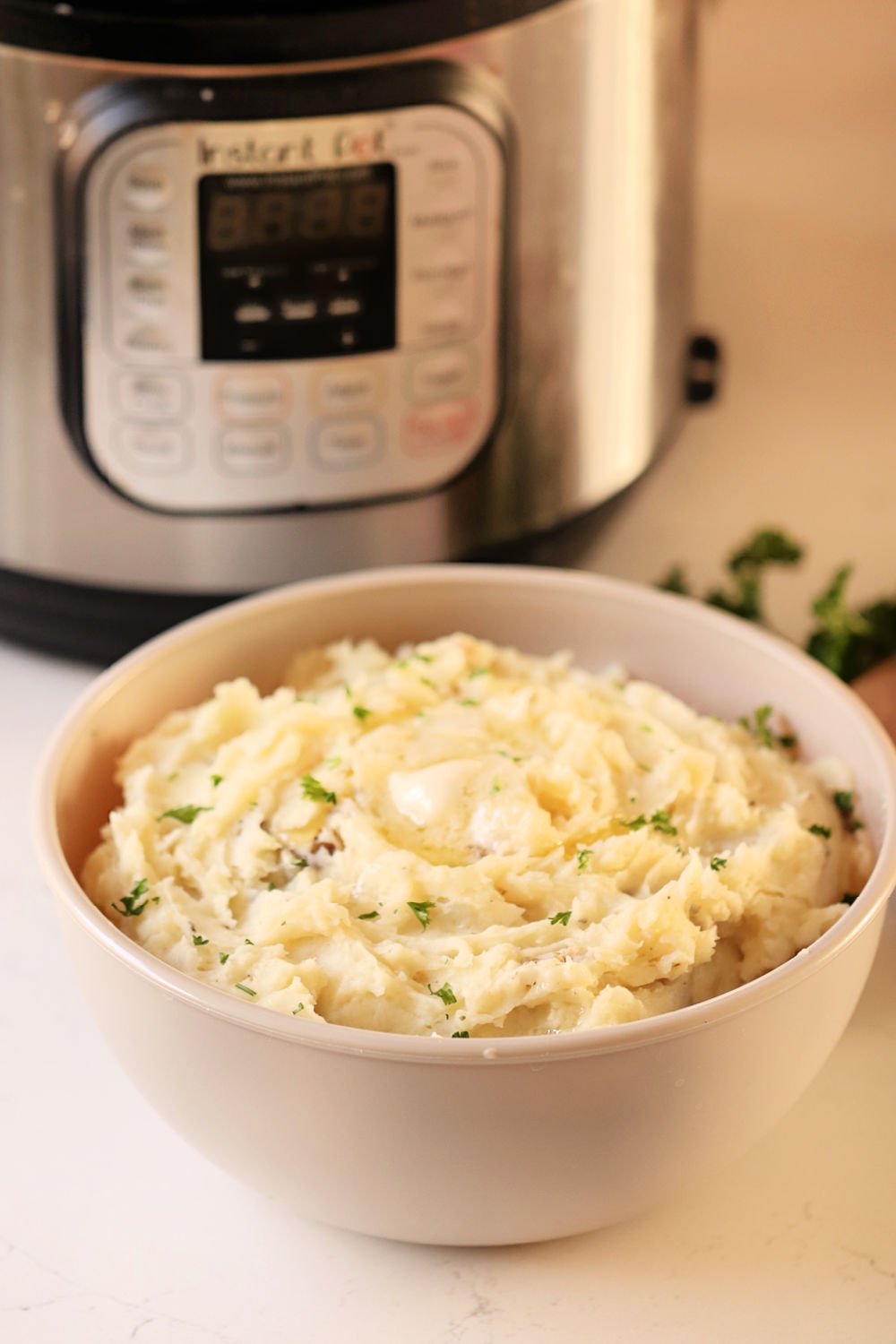 Instant Pot Mashed Potatoes in a bowl with an Instant pot in the back ground.