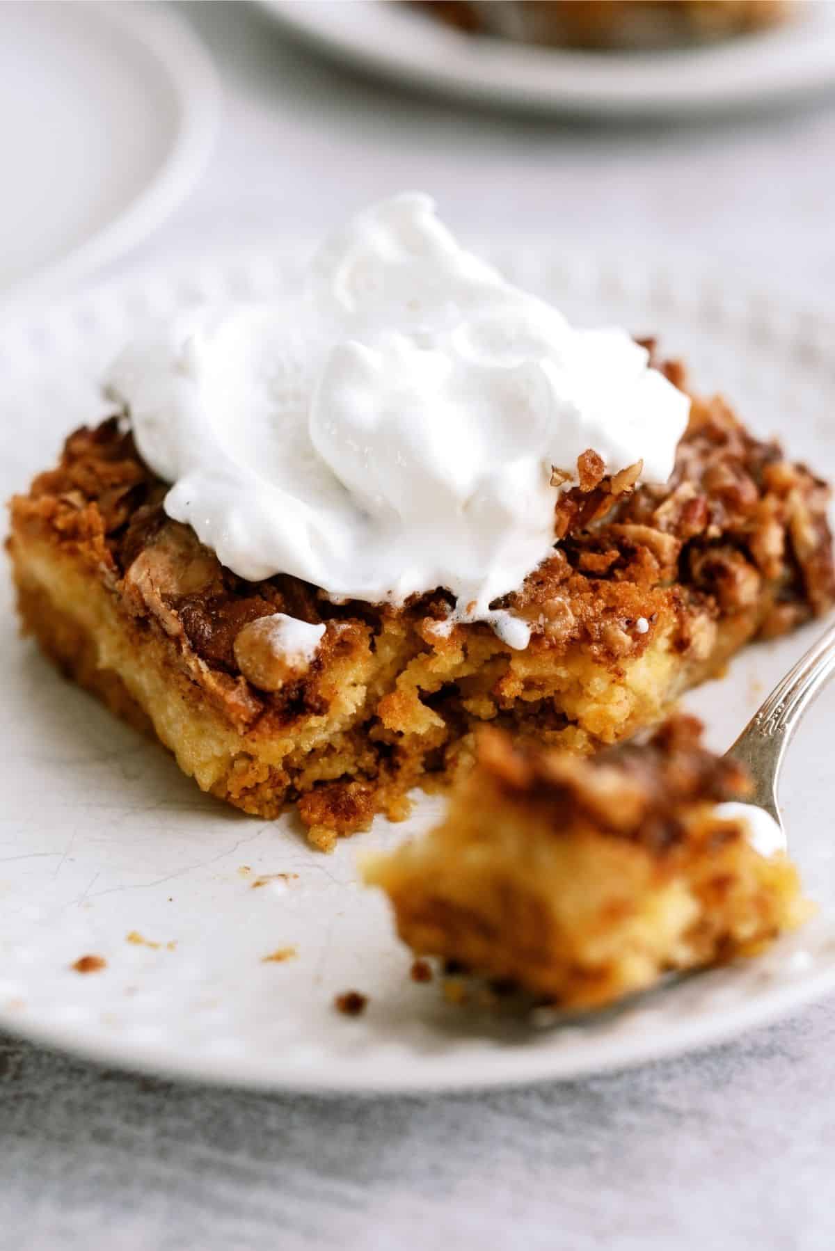 Slice of Pumpkin Dump Cake on a white plate with a fork