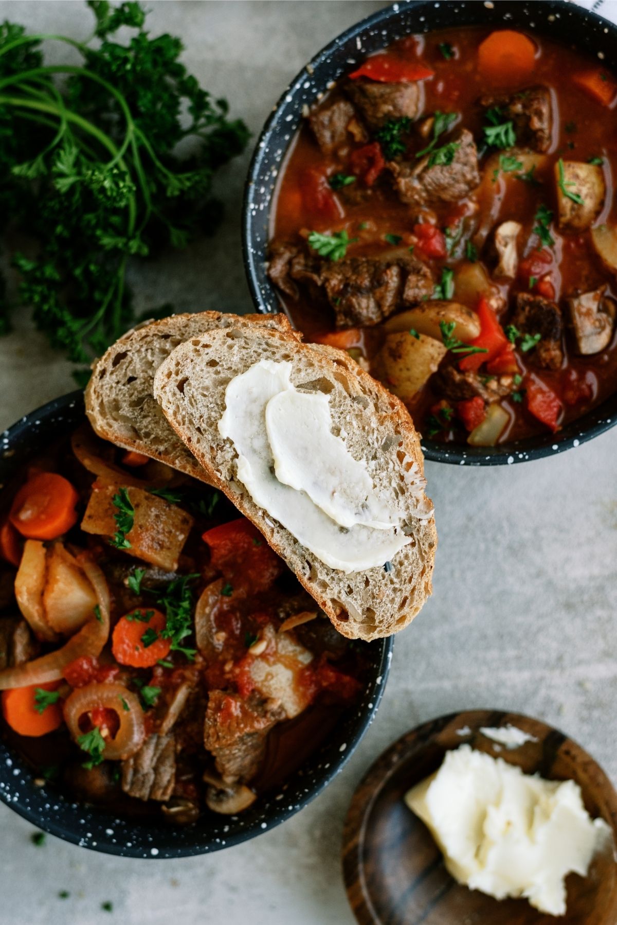 2 bowls of Slow Cooker Chunky Roast Stew with a side of buttered bread