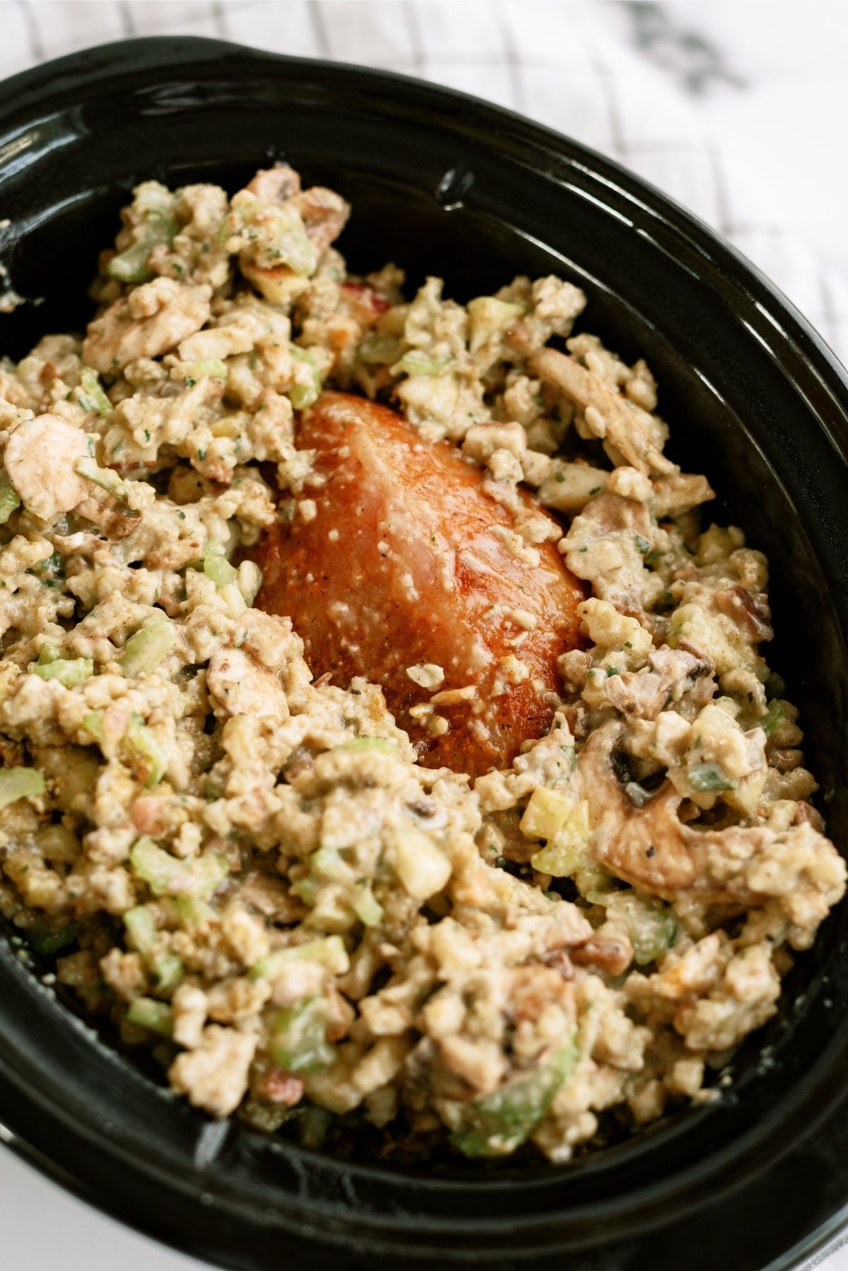 Turkey breast with stuffing on top and sides of it in the slow cooker