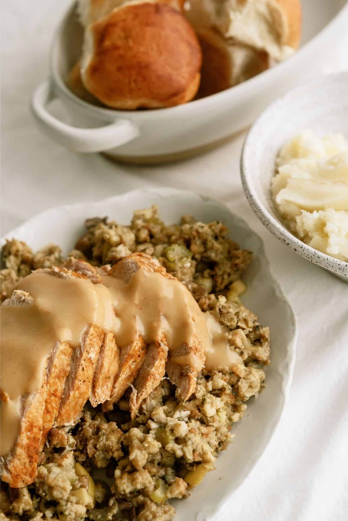 Slow Cooker Turkey and Stuffing on a plate with a side of rolls and potatoes