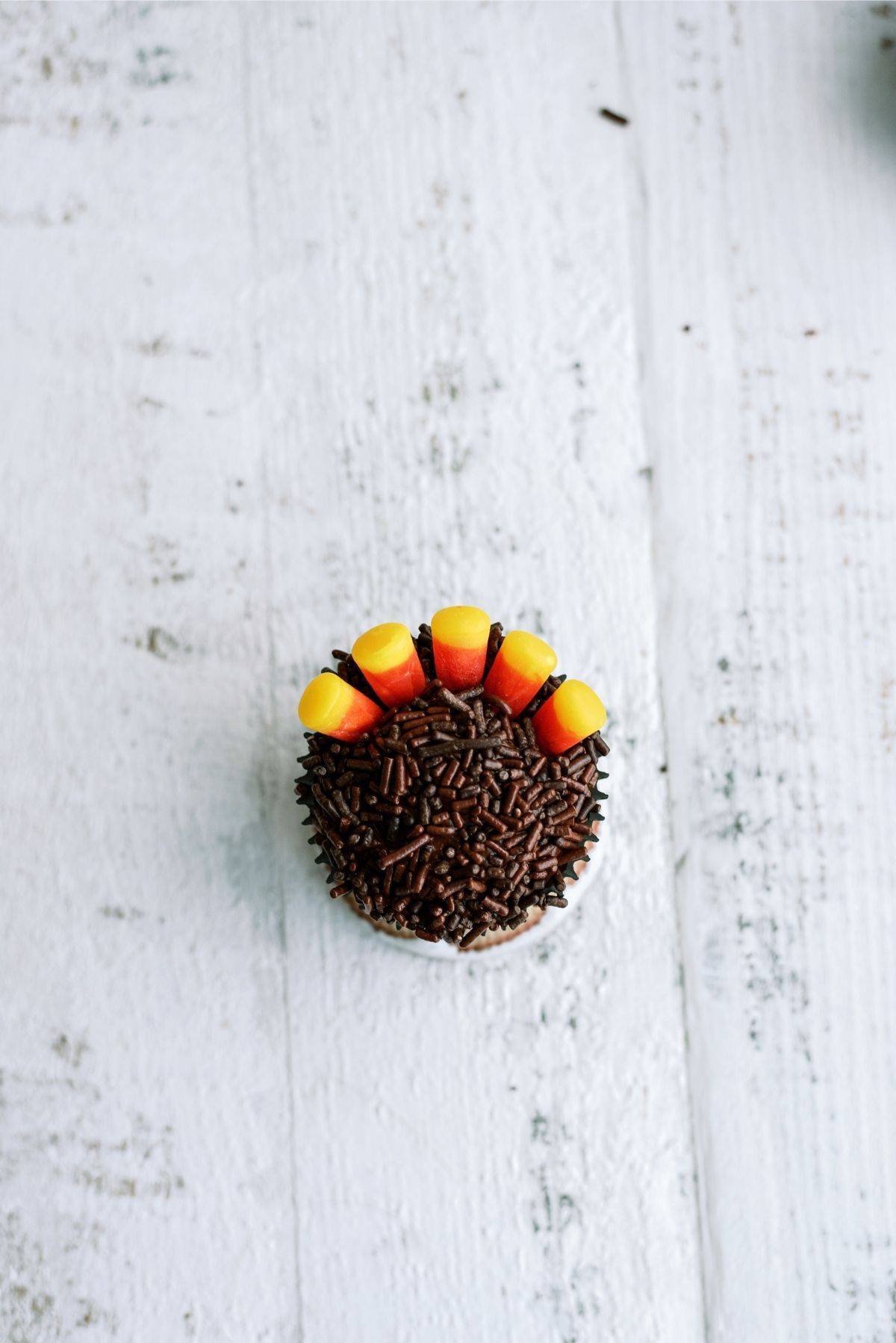 Chocolate cupcake with sprinkles and 5 candycorn pressed into it.