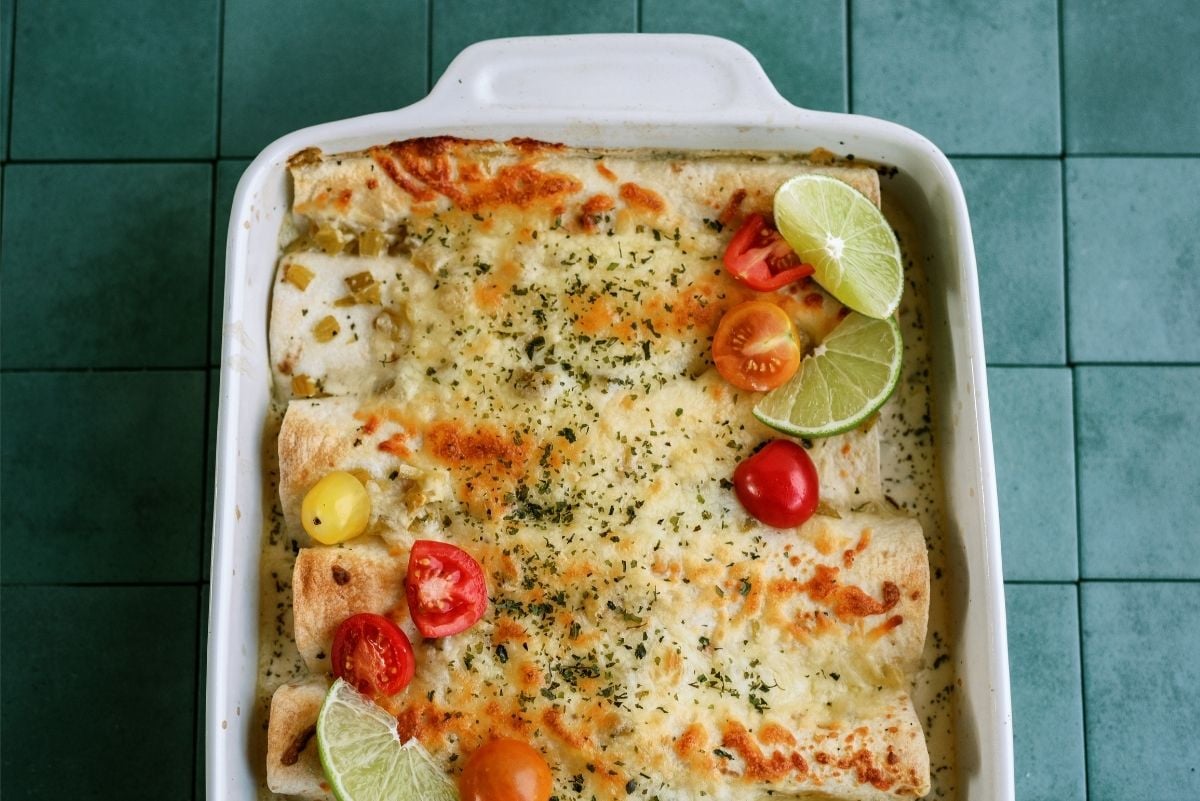 Pan of Turkey Enchiladas topped tomatoes and limes
