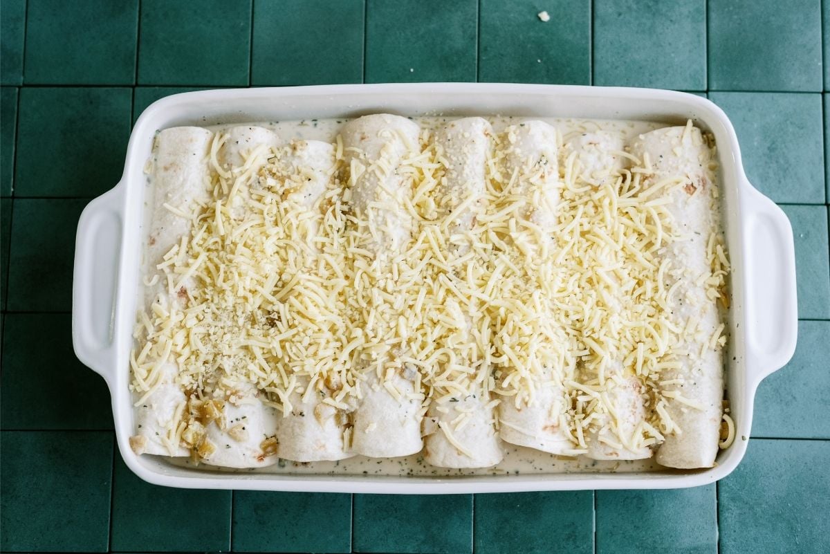 Unbaked Turkey Enchiladas topped with cheese in baking pan