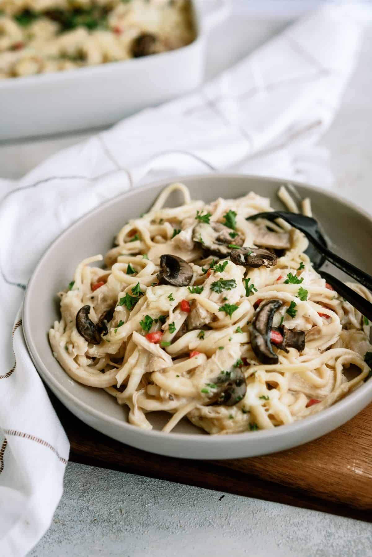 A serving of Chicken Tetrazzini Casserole on a plate with a fork and spoon