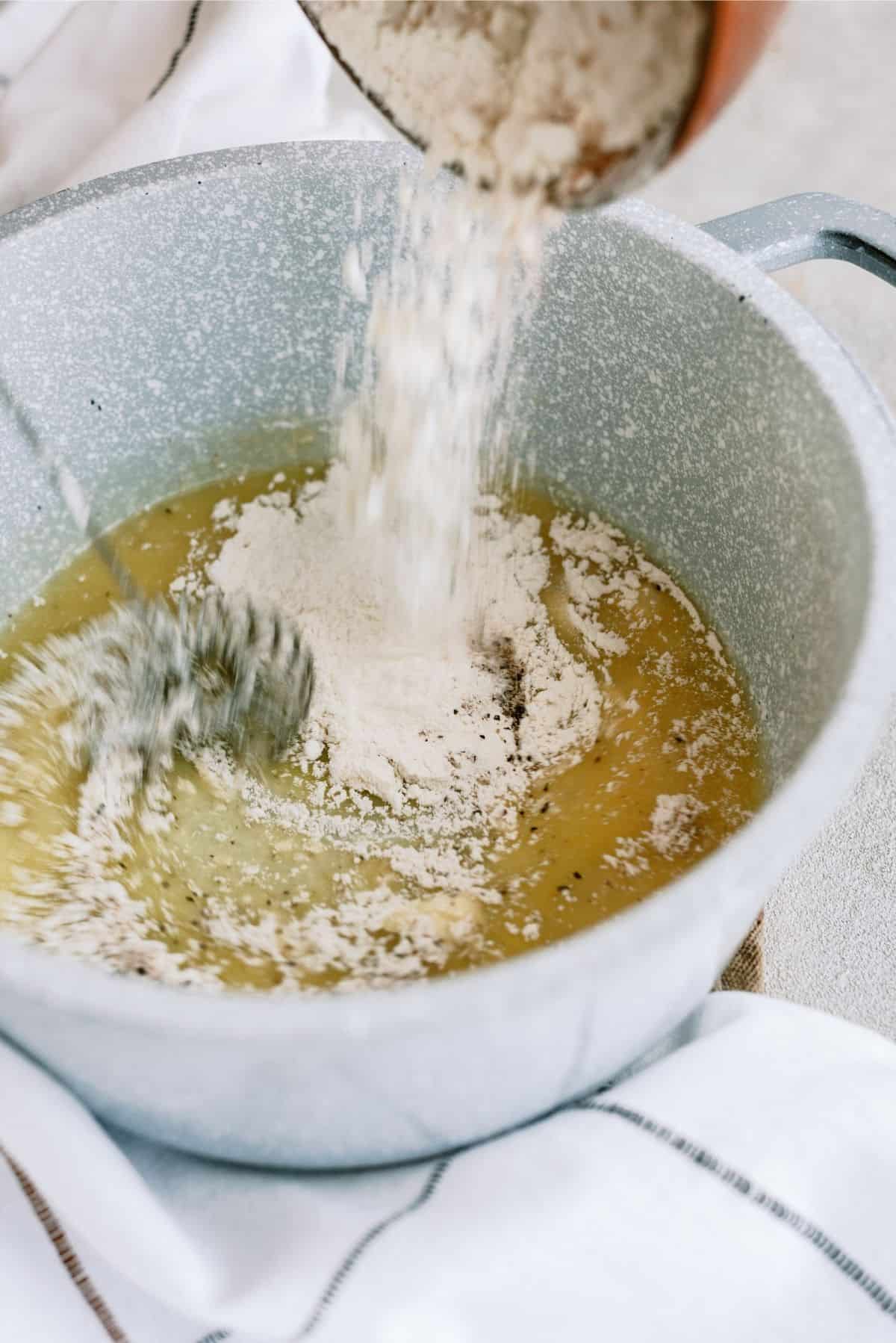 Adding flour and seasonings to a sauce pan with melted butter.