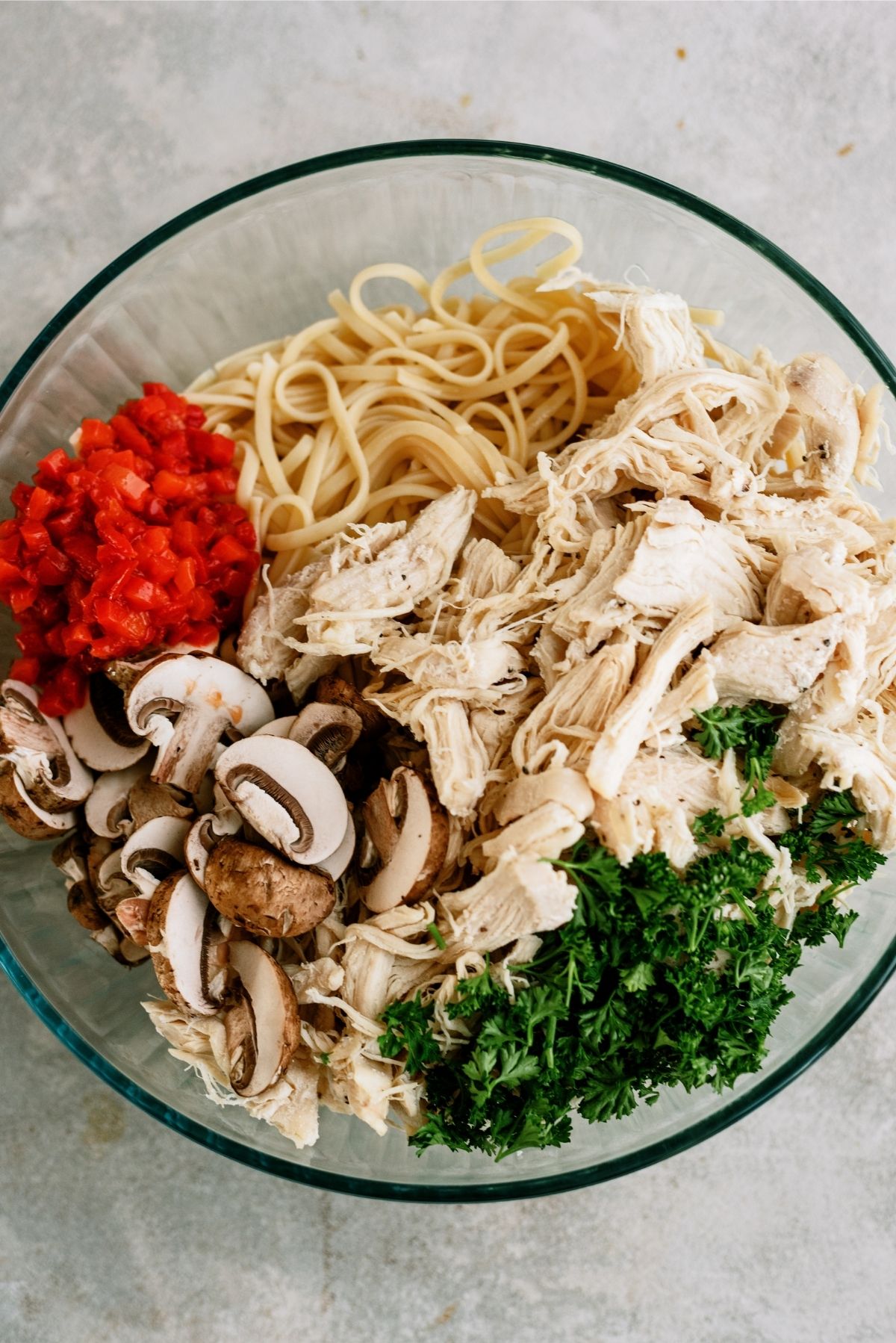 shredded chicken, vegetables and pasta in a large glass bowl