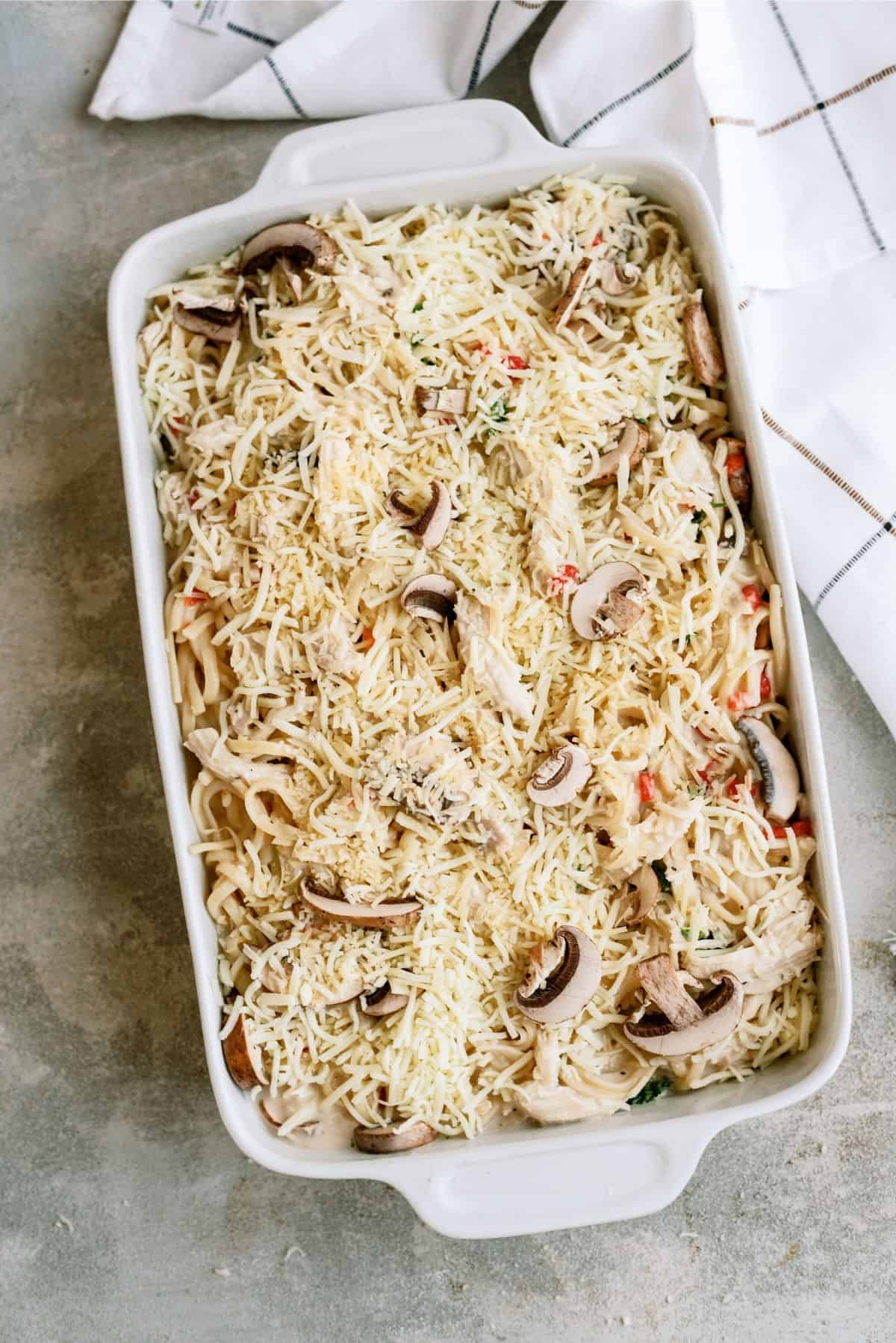 Unbaked Chicken Tetrazzini Casserole in a baking dish topped with cheese