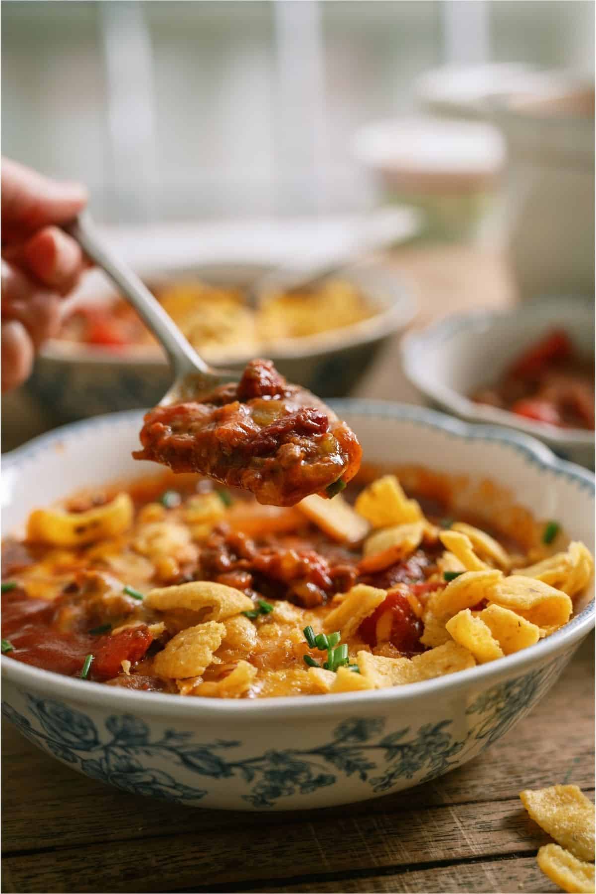 Close up of a bowl of Mom's Crockpot Chili with a spoon lifting out a bite.