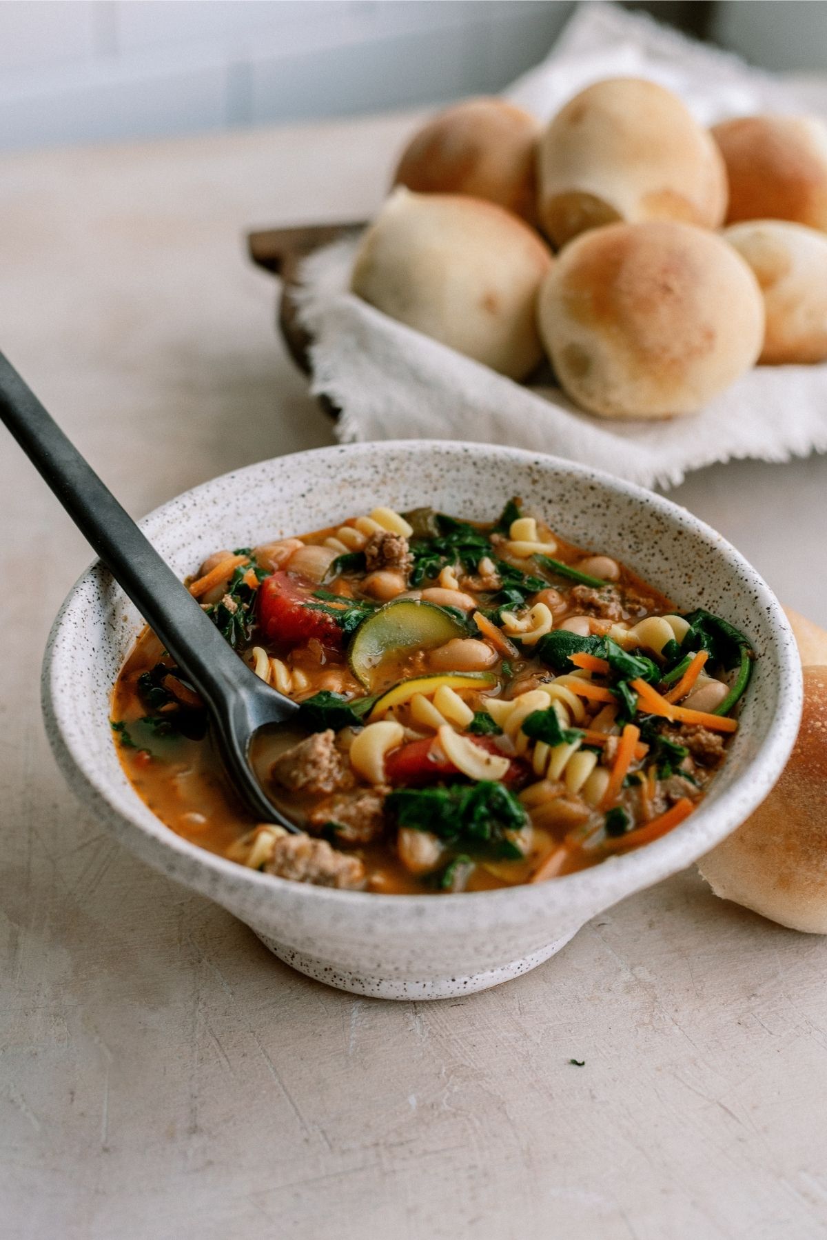 Quick Italian Ground Turkey Soup in a bowl with rolls in the background