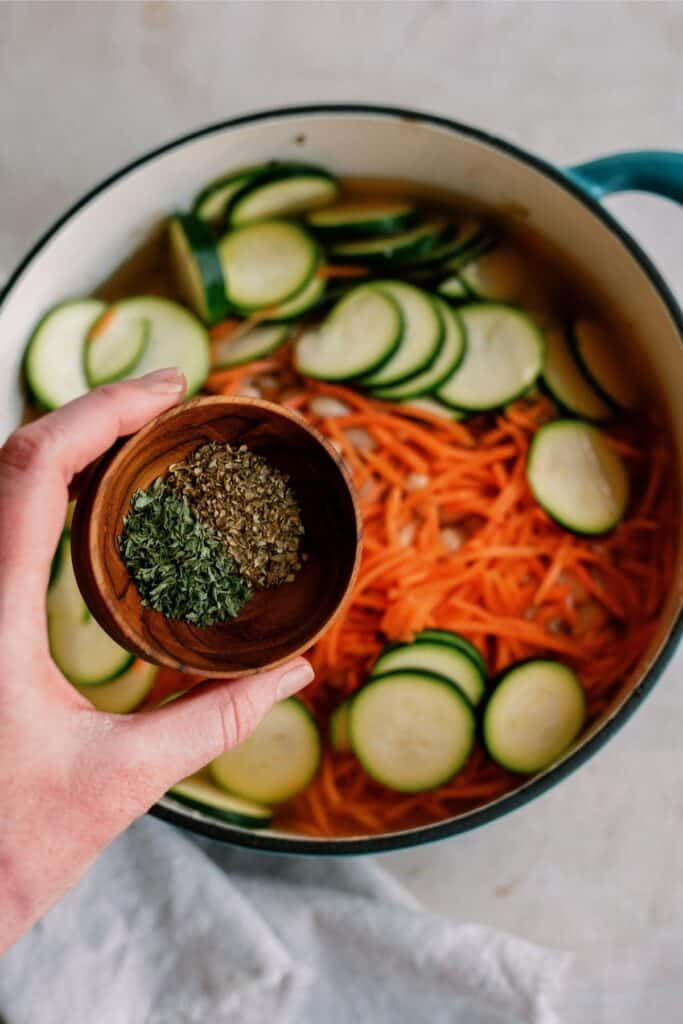 Vegetables and seasoning added to a stock pot.