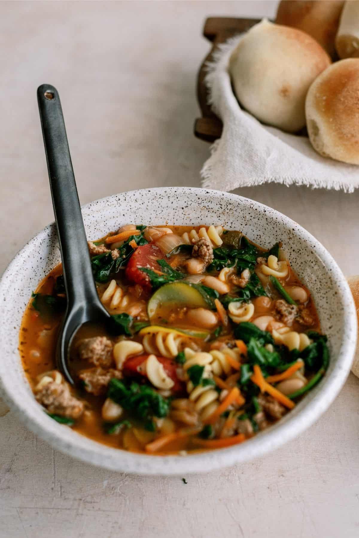 Quick Italian Ground Turkey Soup in a bowl with rolls in the background