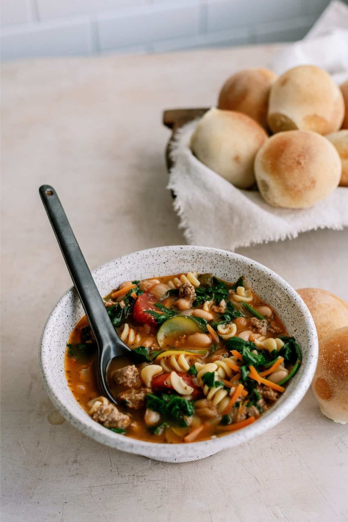 Quick Italian Ground Turkey Soup in a bowl with rolls in the background