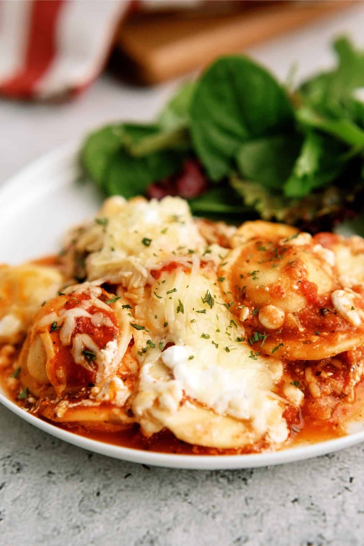 Ravioli Casserole serving on a white plate with spinach