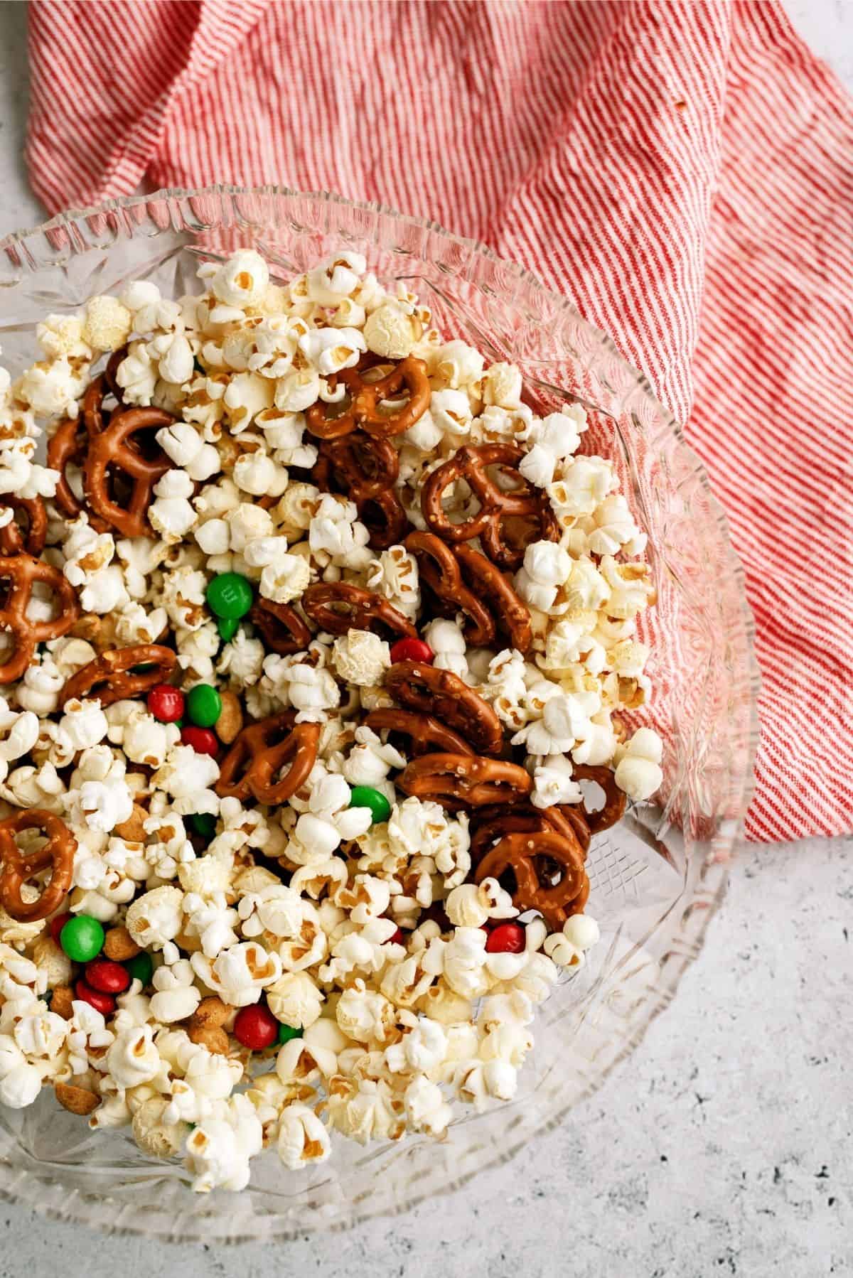 M&M's, pretzels and peanuts added to popcorn in a mixing bowl