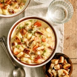 A bowl of Cheesy Ham and Potato Soup with a small bowl of croutons next to it.