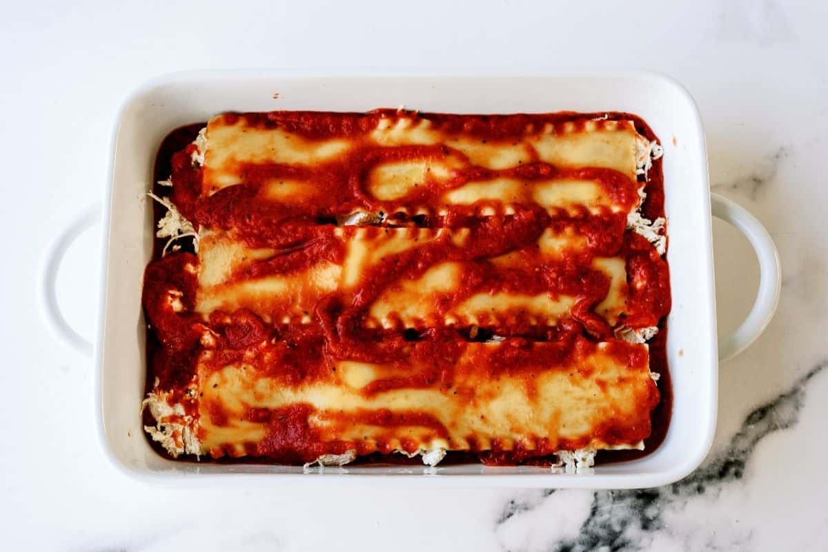 Lasagna noodles on top of chicken mixture topped with sauce