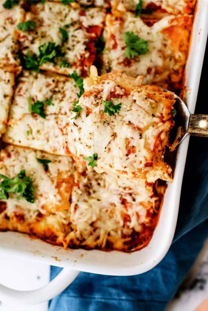 Spatula lifting a piece of Creamy Chicken Lasagna out of the casserole dish.