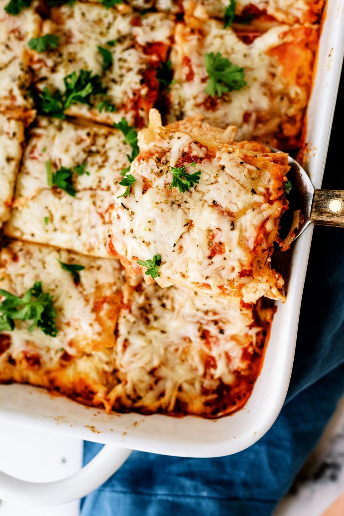 Creamy Chicken Lasagna in 9x13 dish with a serving spoon lifting a slice out