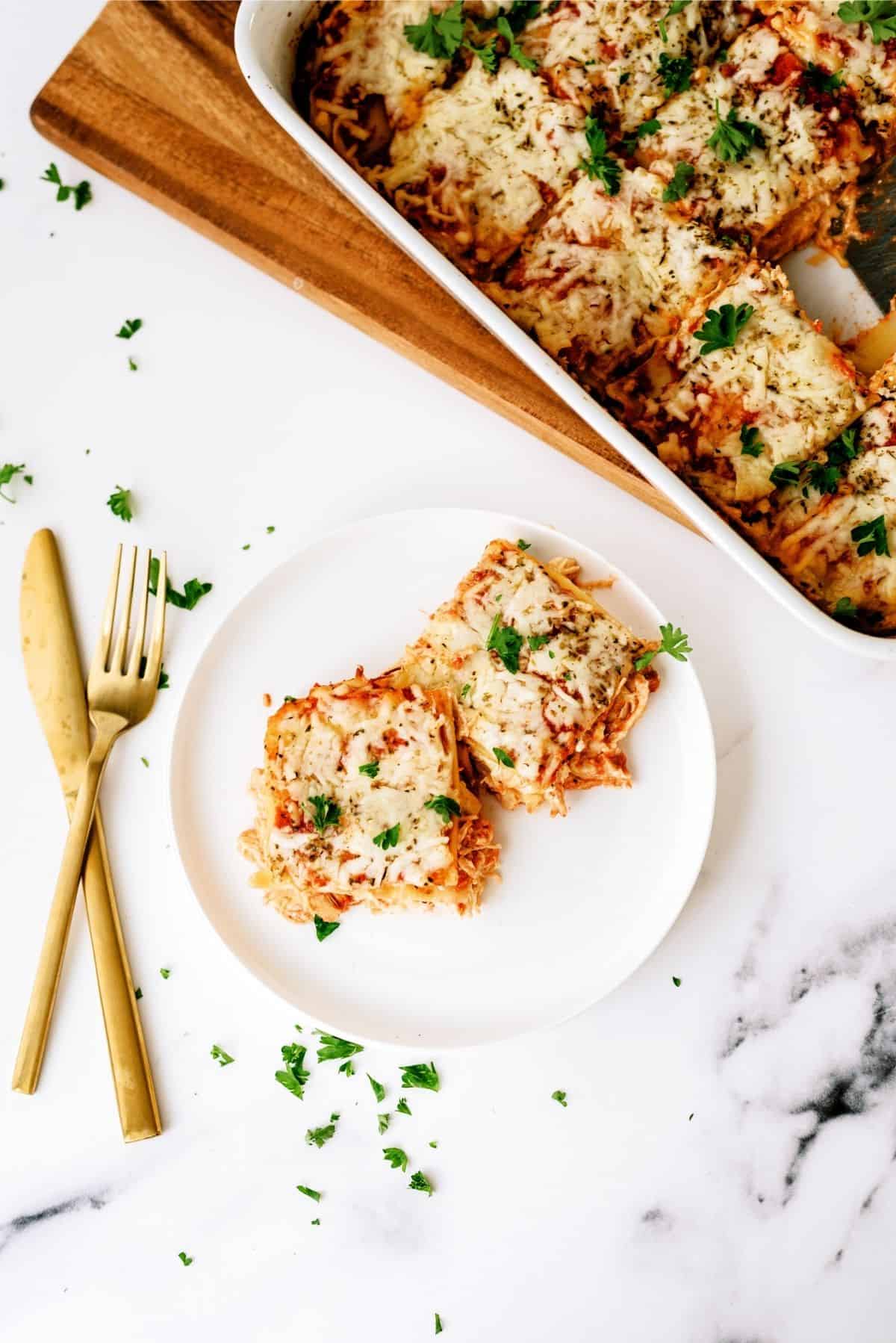 2 squares of Creamy Chicken Lasagna on a white plate with gold silverware