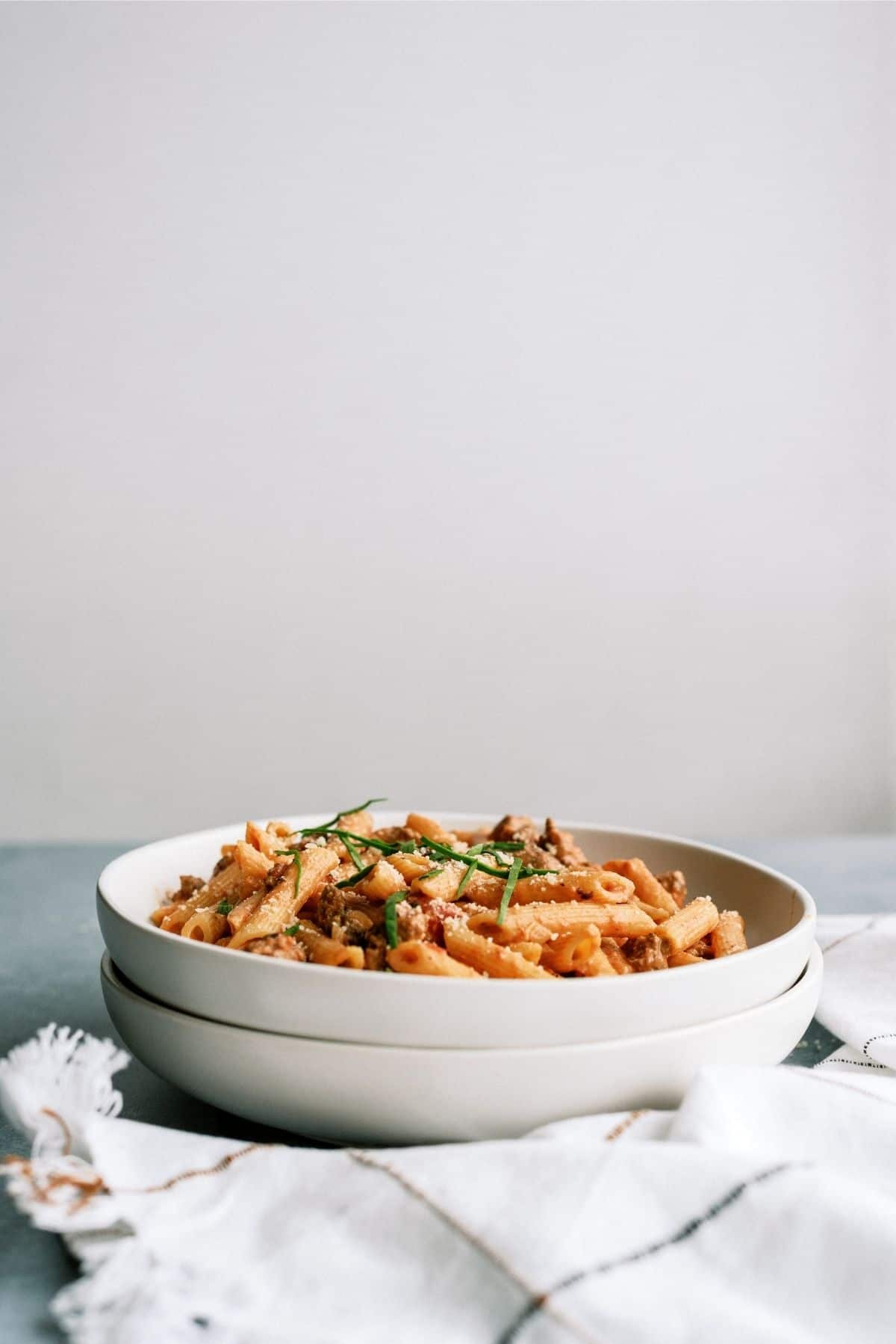 2 bowls stacked one filled with Creamy Sausage and Tomato Pasta