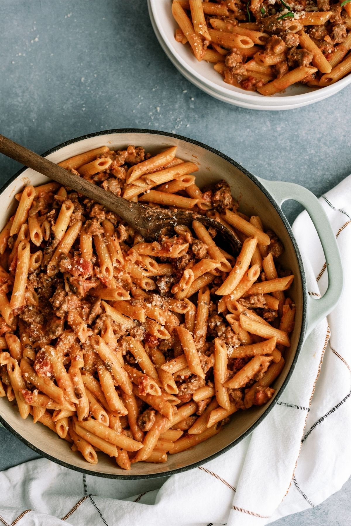 Pan of Creamy Sausage and Tomato Pasta with a wooden spoon