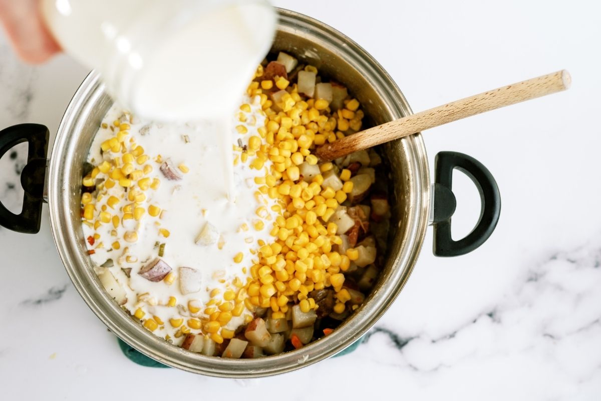Adding cream and corn to soup mixture in stock pot
