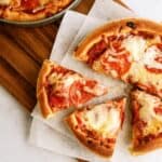 Homemade Pizza Hut Original Deep Dish Pizza sliced on a cutting board