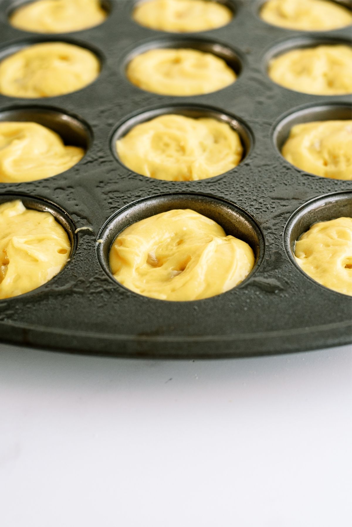 Unbaked Mini Pineapple Upside Down Cakes in muffin tin