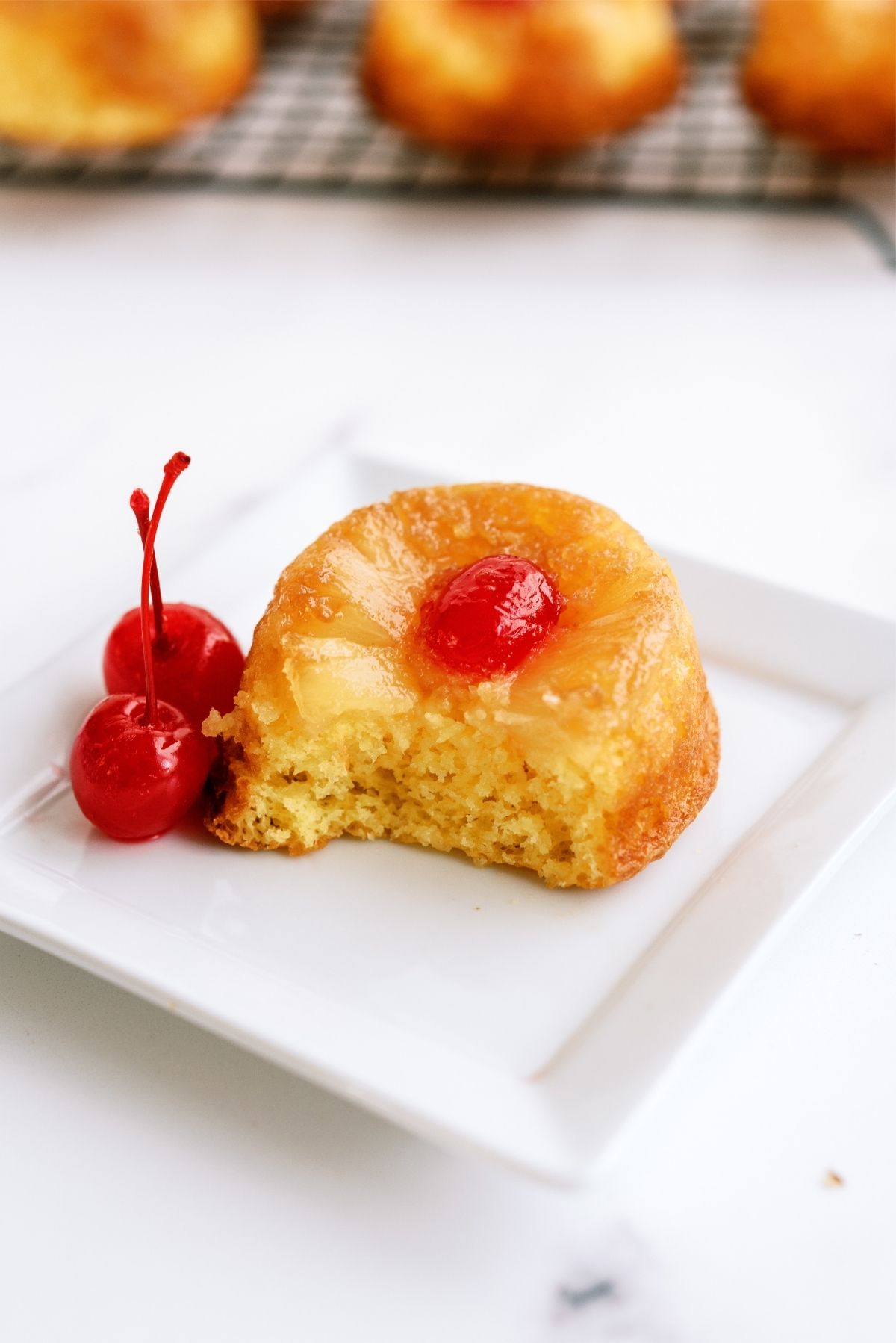 Mini Pineapple Upside Down Cake on a plate with a bite taken out of it.