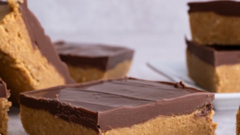 Finished no bake peanut butter bars, cut and displayed at different angles so you can see the layers of peanut butter and chocolate