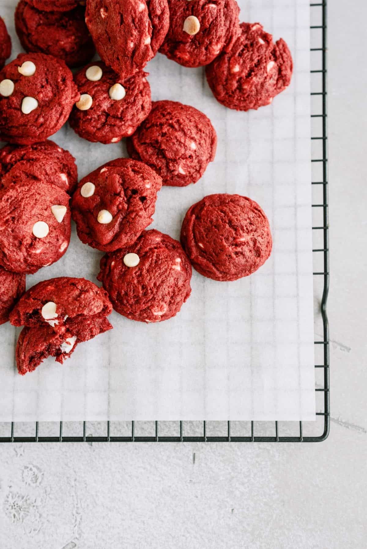 Red Velvet White Chocolate Chip Cookies on parchment paper on a cooling rack