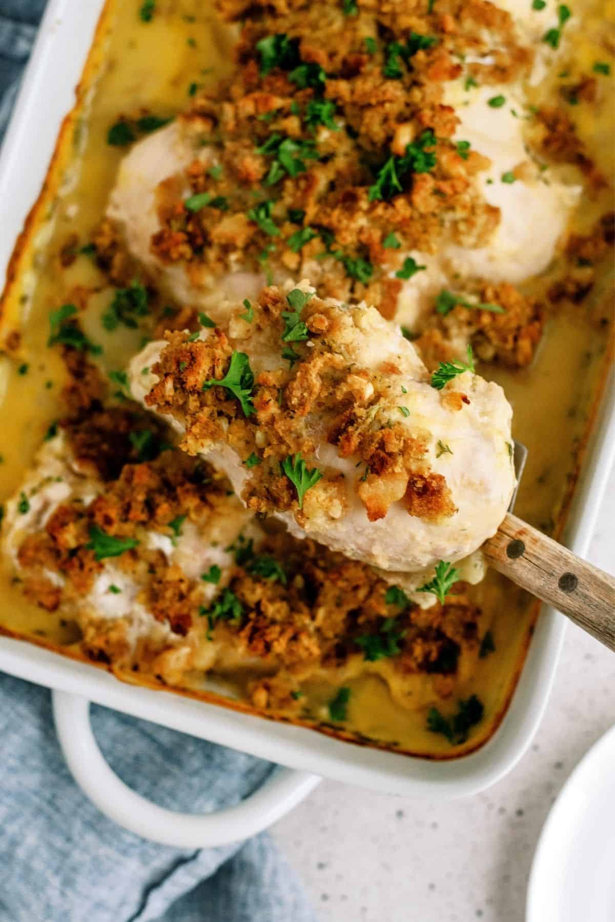 Savory Chicken and Stuffing Bake with a spoon lifting a piece of chicken out of the dish