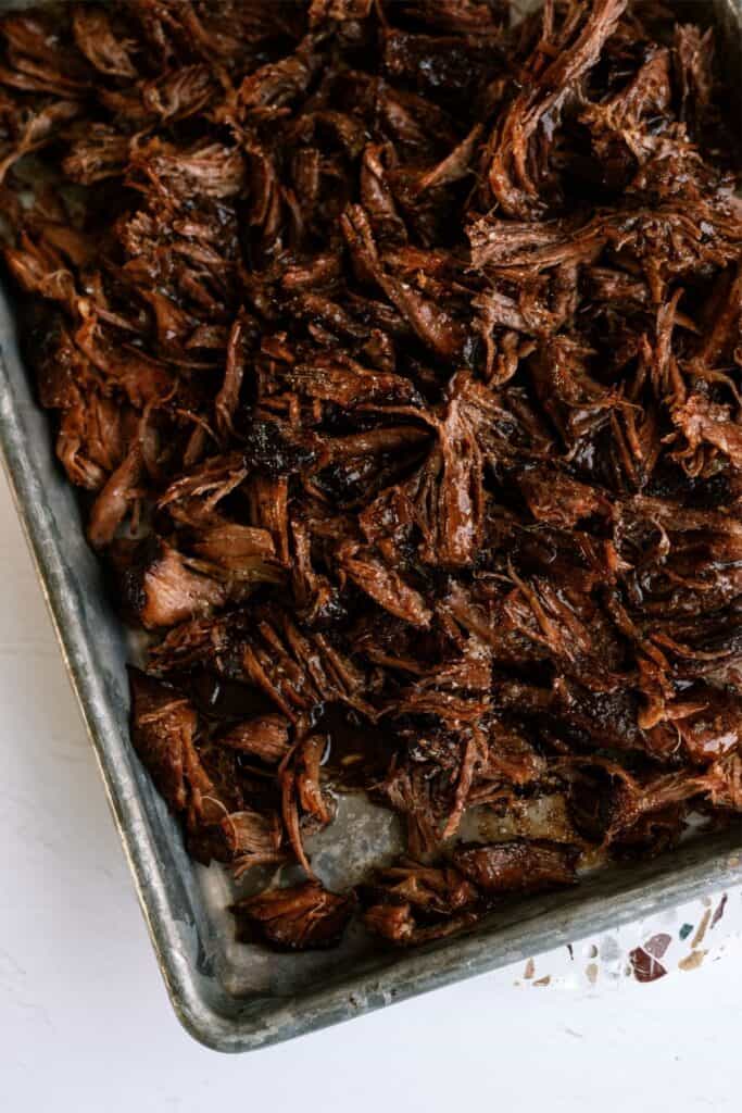 Slow Cooker Italian Roast Beef shredded on a baking sheet.