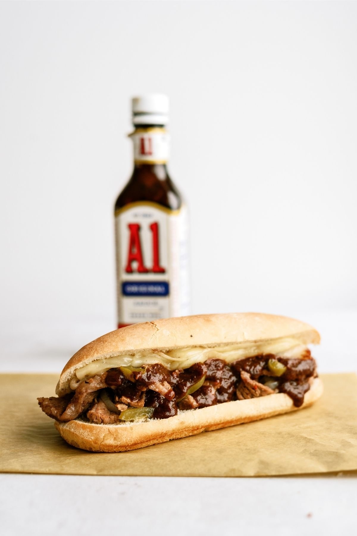 Slow Cooker Philly Cheese Steak Sandwich on a plate with a bottle of A1 in the background