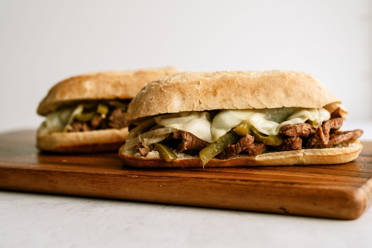 2 Slow Cooker Philly Cheese Steak Sandwiches on a cutting board