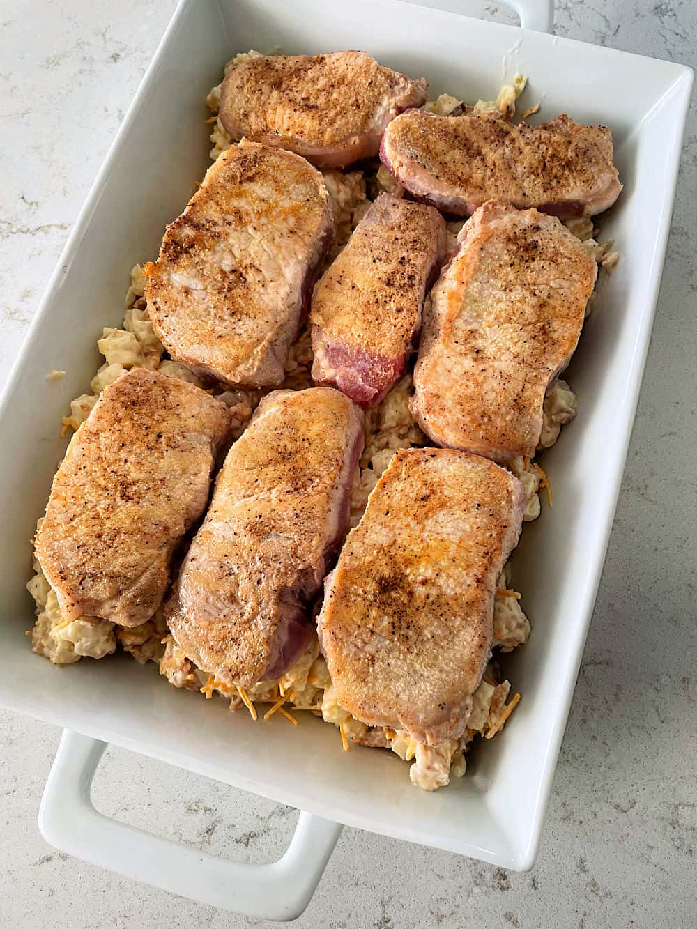 Unbaked Pork Chop and Hashbrown Casserole in a casserole dish