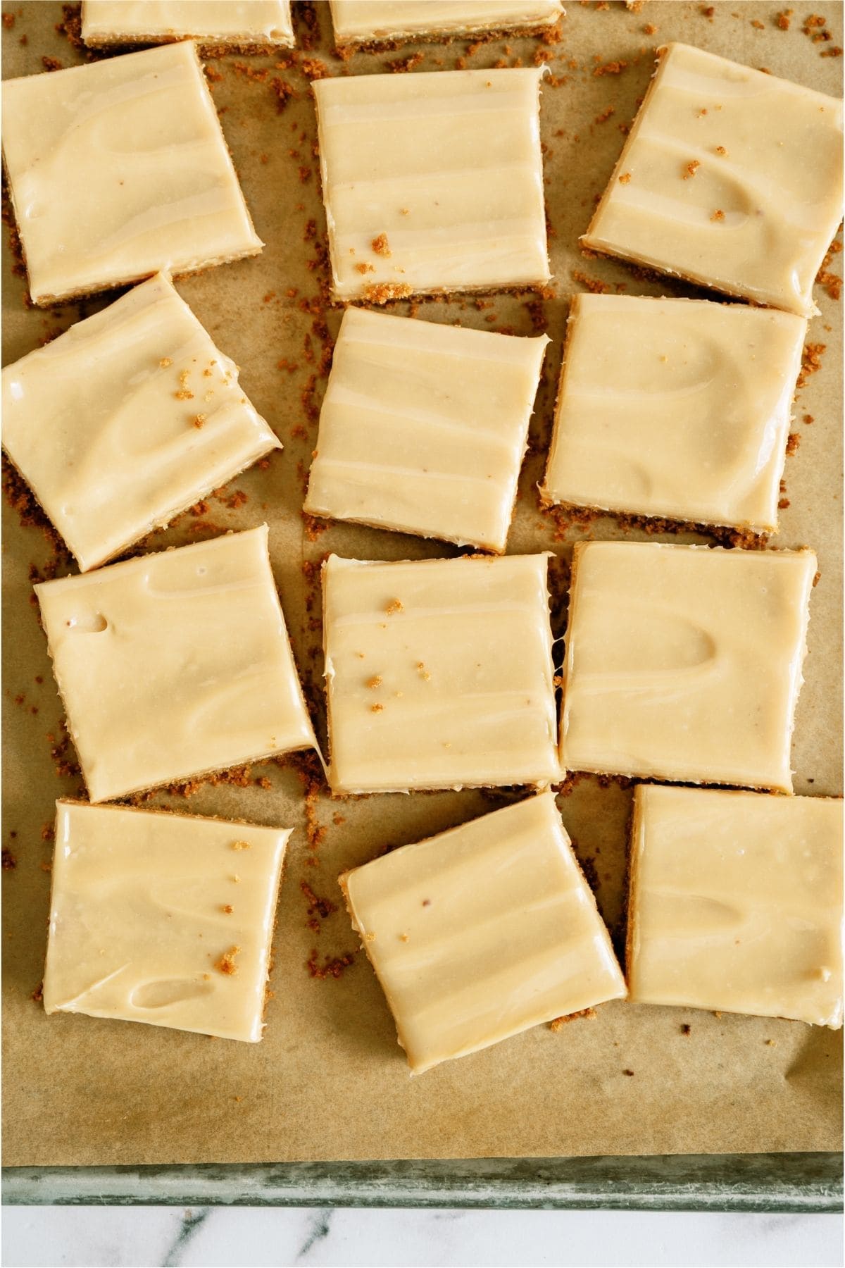 Top view of Caramel Cheesecake Bars cut into squares on a baking sheet.