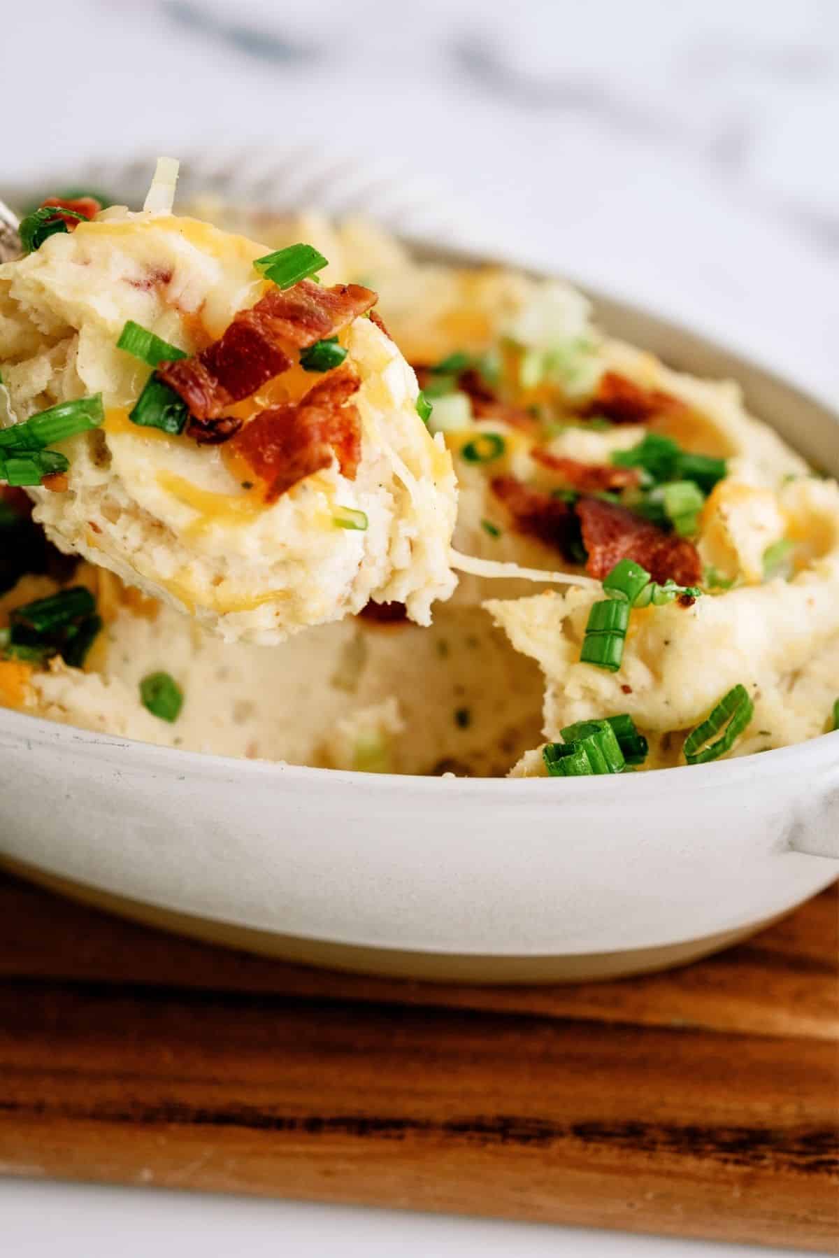 Cheesy Ranch Potatoes in a baking dish with a spoon scooping out a serving