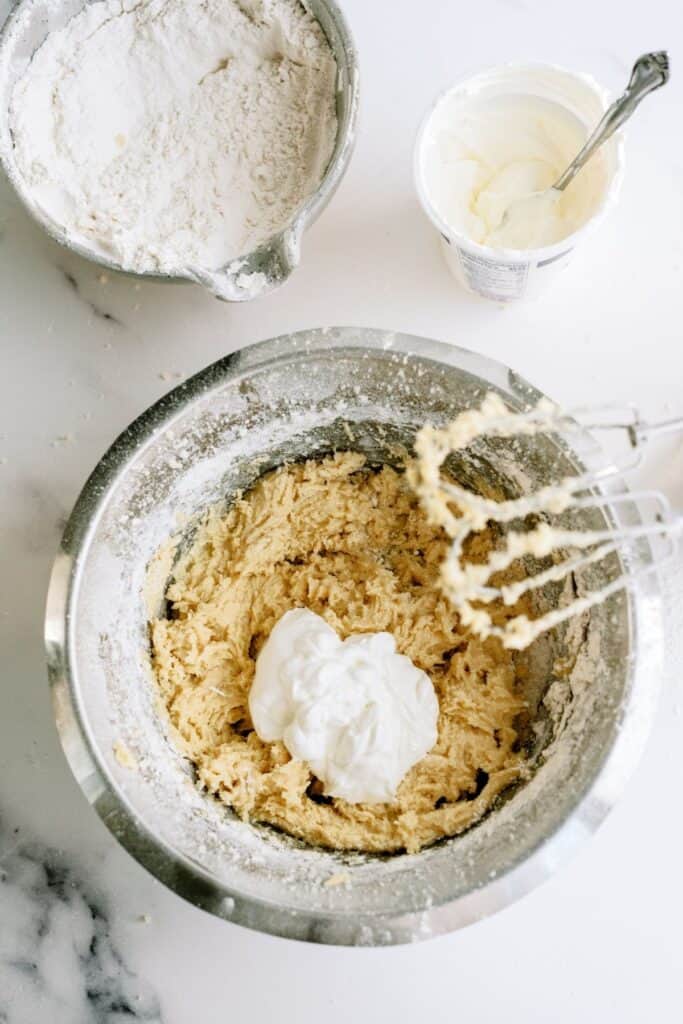 Bread dough ingredients in a mixing bowl with a hand mixer.
