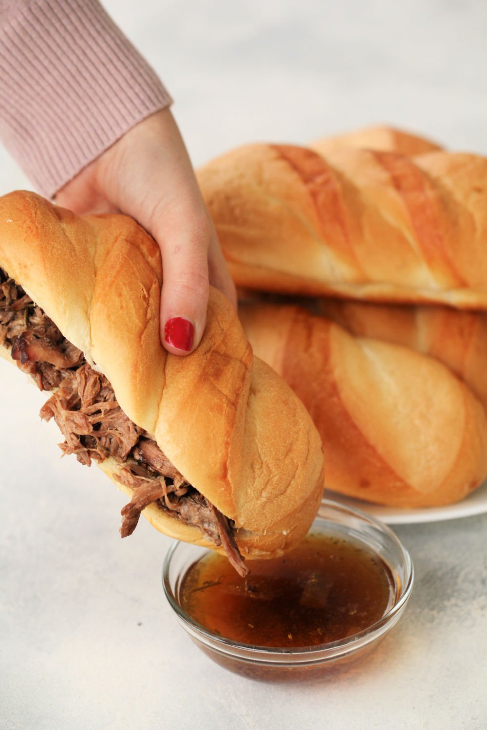 Dipping Instant Pot French Dip Sandwiches in AuJu sauce