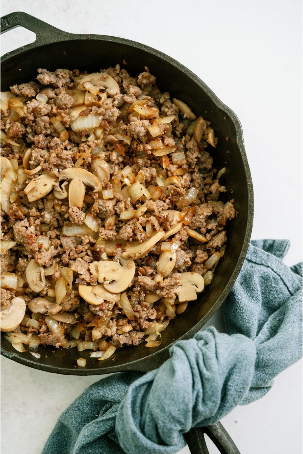Italian sausage in a skillet with mushrooms.