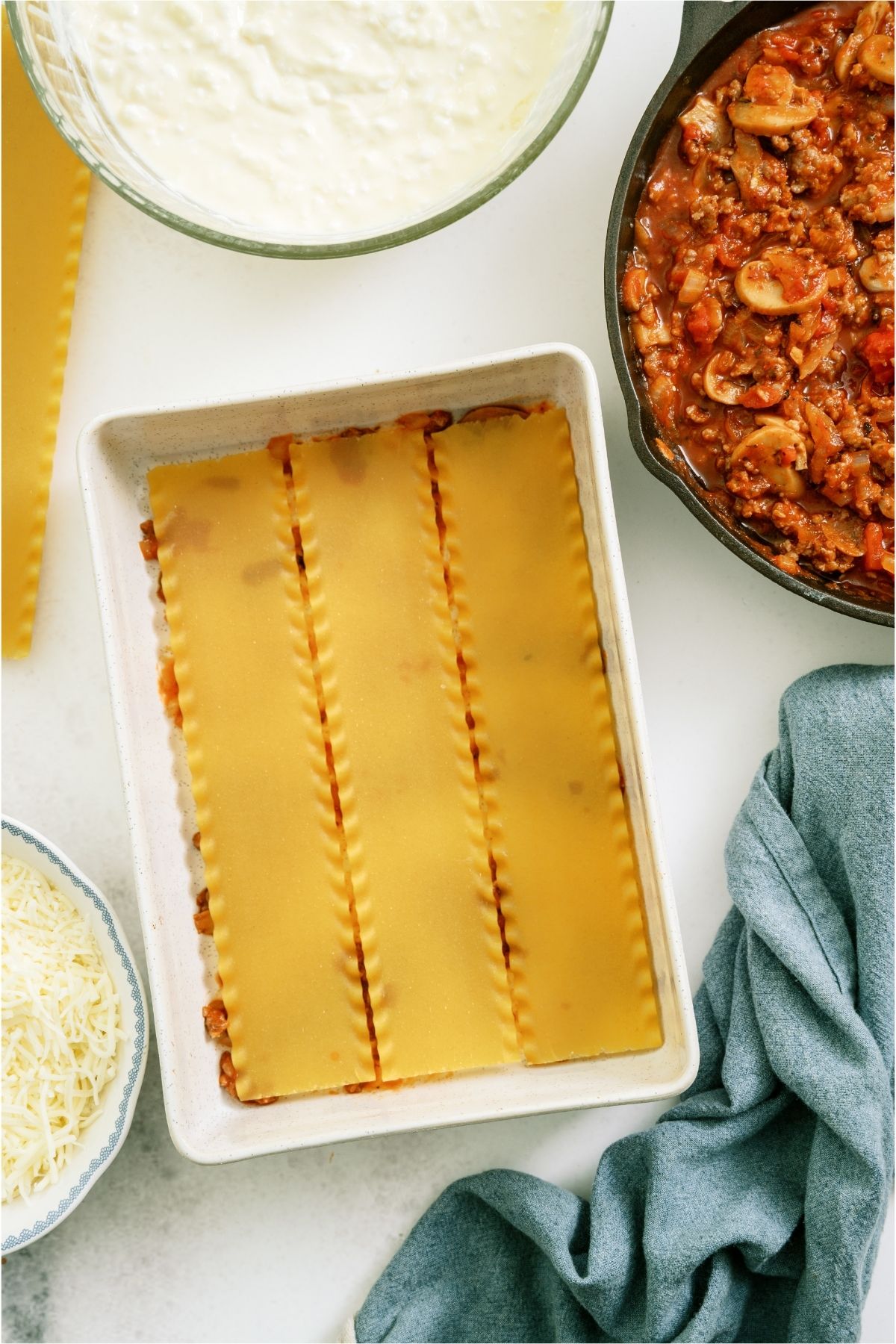 Lasagna noodles in a casserole dish on top of a thin layer of sauce.